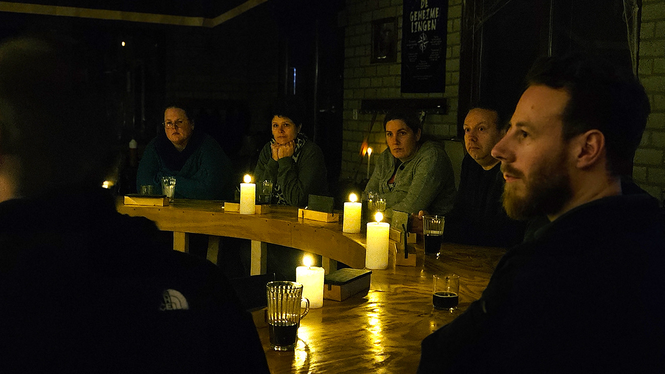 Spelers rond de tafel bij kaarslicht tijdens De Geheimelingen